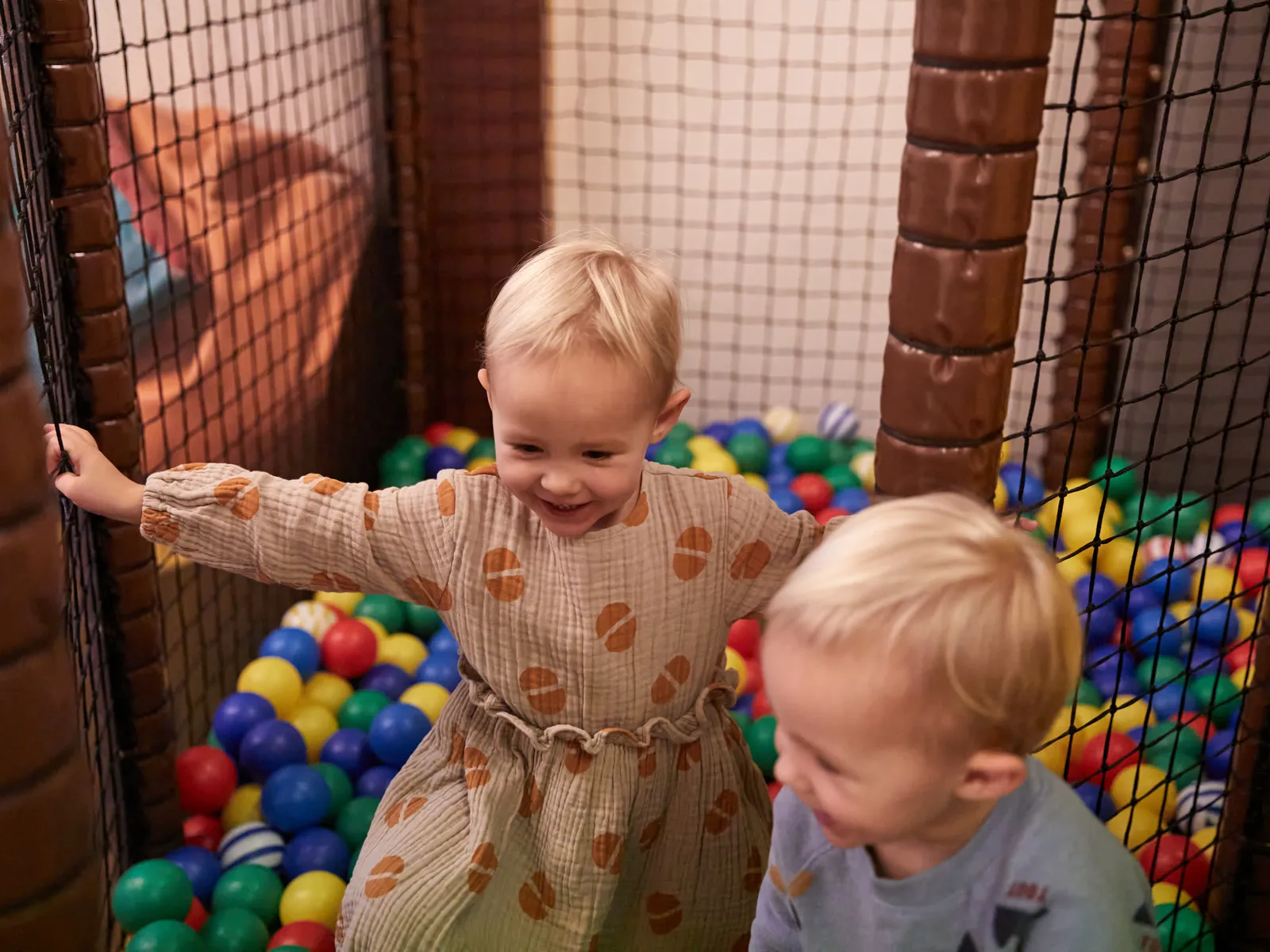 Two children playing in a ball pit with colorful balls
