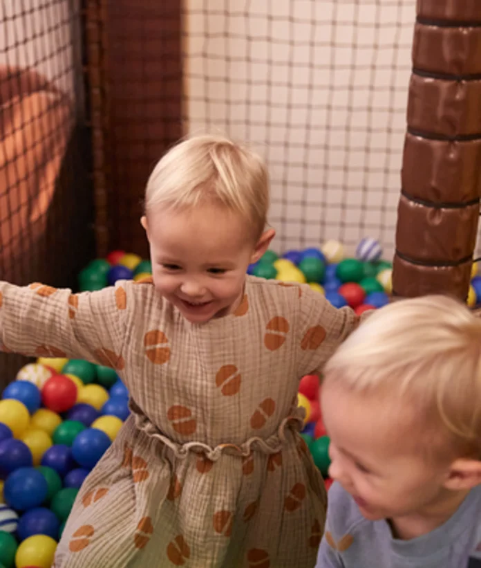 Zwei Kinder spielen in einem Bällebad mit bunten Bällen