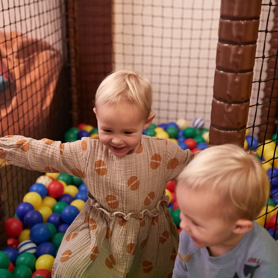 Zwei Kinder spielen in einem Bällebad mit bunten Bällen