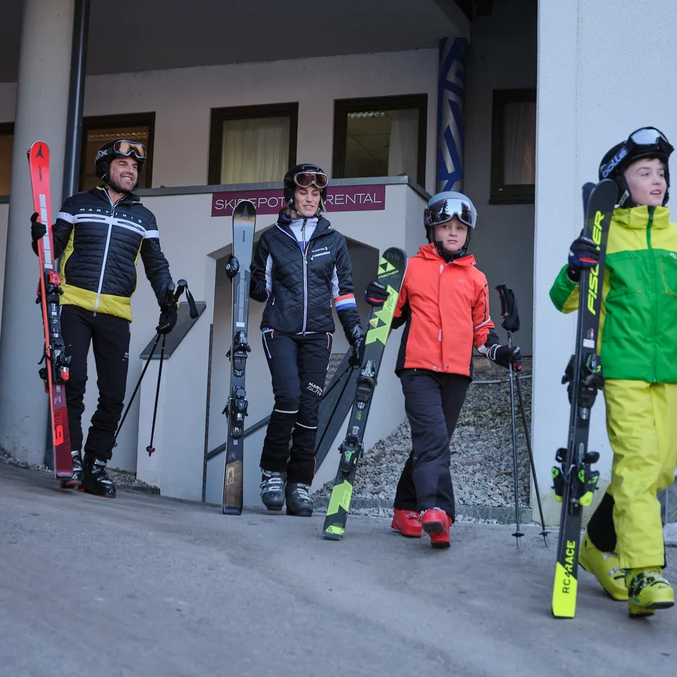 Familie mit Skiern vor Skiverleih