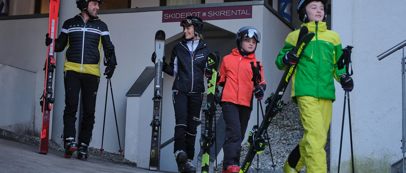 Familie mit Skiern vor Skidepot Skirental